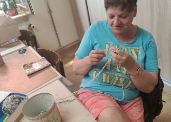 Powiększ zdjęcie: kobieta przy stole wykonuje pracę na szydełku