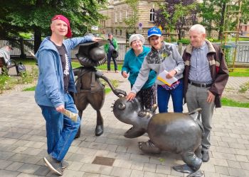 Powiększ zdjęcie: cztery osoby stoją w okolicach Ratusza w Bielsku-Białej przy pomniku Pampaliniego i hipopotama