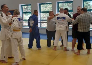 Powiększ zdjęcie: grupa podopiecznych podczas treningu judo z trenerem na sali gimnastycznej