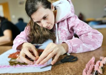 Powiększ zdjęcie: uczestniczka zajęć wykonuje wyszywankę
