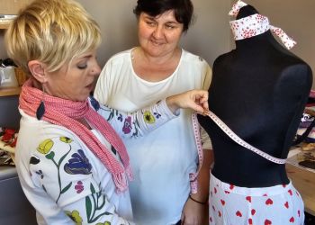 Powiększ zdjęcie: terapeutka i uczestniczka zajęć stoją przy manekinie, terapeutka mieży metrem jego obwód