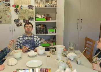 Powiększ zdjęcie: troje uczestników - dwie kobiety i mężczyzna podczas zajęć w pracowni ceramicznej przy stole